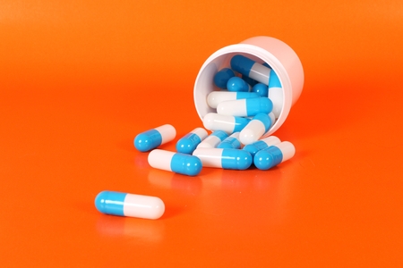 Blue and white capsules are lying in the orange studio