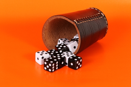 black and white dices are lying in the orange studio with a cup