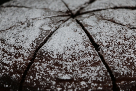 Extreme close up of a sliced chocolate cake with powder on the topの写真素材