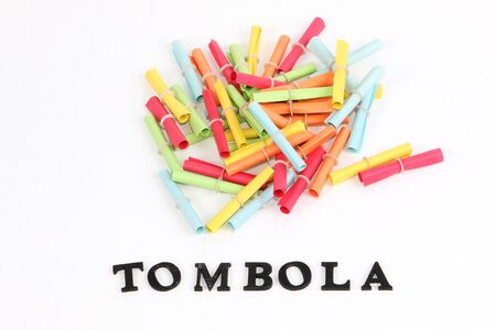 Heap of colorful tombola tickets in the white studio with a tombola letter in the front with wooden lettersの写真素材