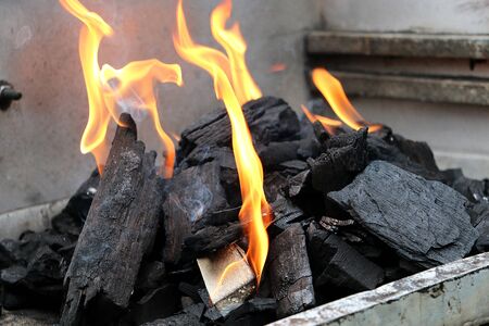 Close up of flames between the charcoal in the barbecue grill