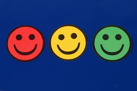 Three cut out traffic lights colored smileys lying on a blue background in the studioの写真素材