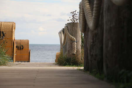 beautiful view to the beach between beach chairs and planks with a large ropeの写真素材
