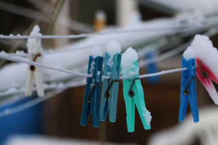 Colorful clothespins hang on the clothesline covered by snowの写真素材
