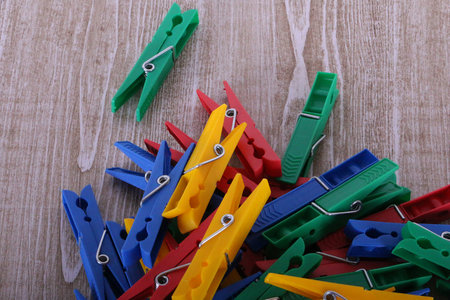 Heap of colorful plastic clothespins are lying on a wooden table