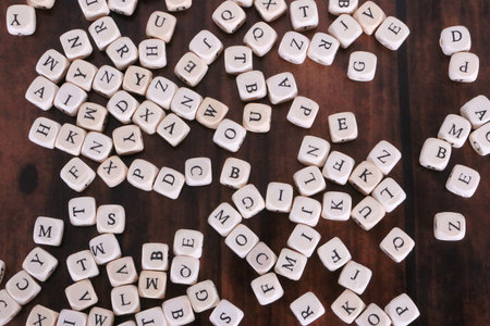 Close-up of a lot of small cubes with letters on them lying on a wooden table