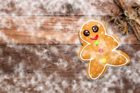 Christmas homemade gingerbread cookies over wooden background with falling snow