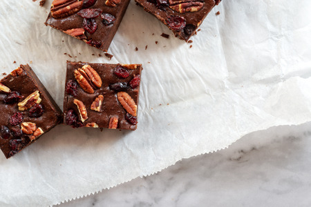 homemade chocolate fudge brownies with pecan nut and dried canberry on white baking paper background.の写真素材