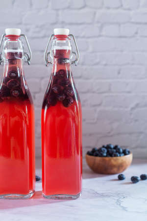 bottles of homemade blueberry kombucha drink on marble floor, fermented tea drinks