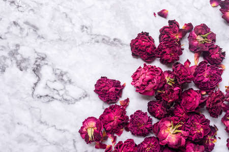 dried organic pink rose buds on white marnle table background.の写真素材
