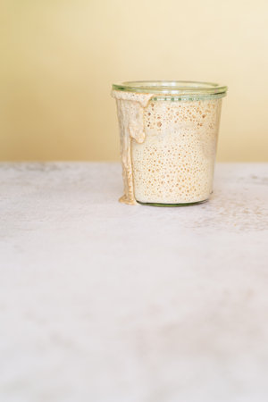 new sourdough starter in glass jar on withe marble tableの写真素材