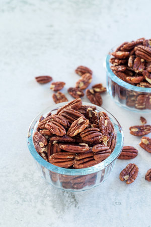 roasted pecan nut in glass bowl on white table background.