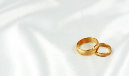 Golden wedding rings on white silk の写真素材