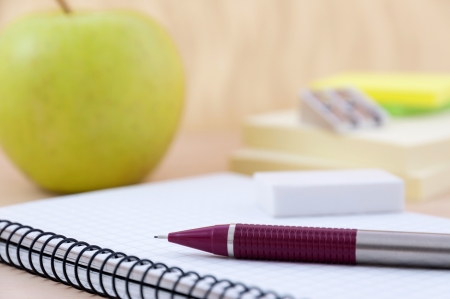 Writing equipment on desk with appleの写真素材