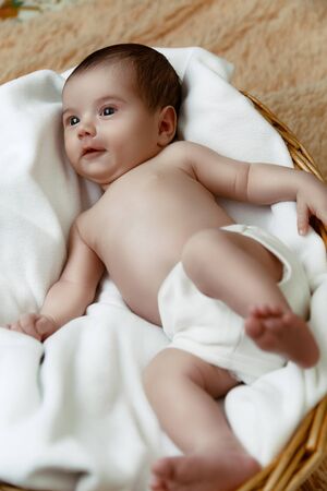 Cute smiling newborn baby lying in wicker basket