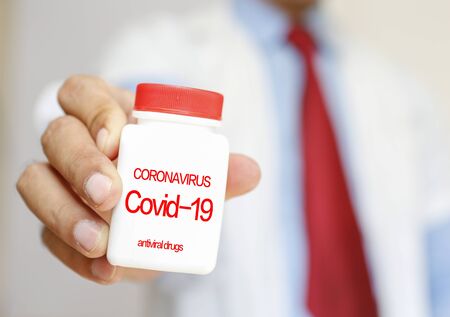 The doctor's hand is carrying medication for the corona virusの写真素材