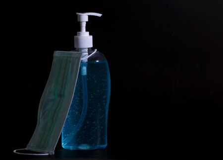 Hand sanitizer antibacterial antiseptic gel and face mask  on dark background. Covid-19 prevention and health protection conceptの写真素材