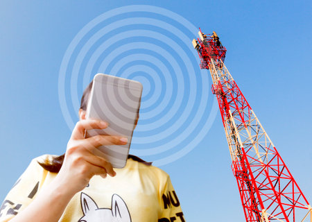A girl holding a smartphone and background is a telephone pole.の写真素材