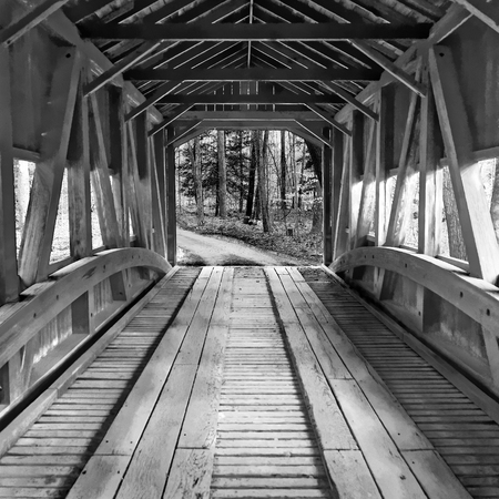 Interior of an old historical vintage covered wooden bridge crossing a river or creek leading out...