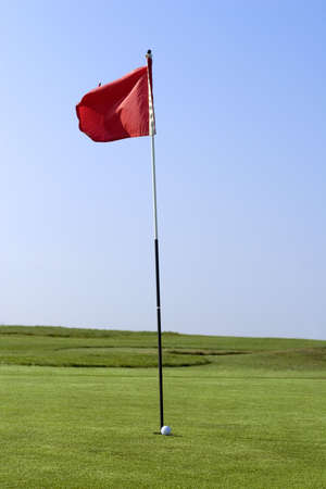 A putting green with flag and golf ballの写真素材