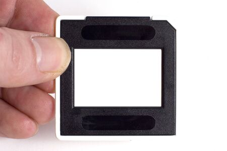 A hand holding a film slide, the centre portion of the slide is blank so an image can be insertedの写真素材