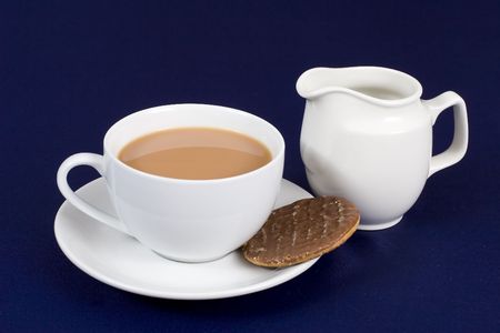 A cup of tea with a chocolate biscuit and milk jugの写真素材