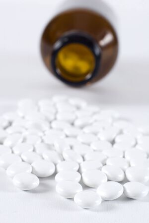 Pills spill out of an open bottle, limited depth of field focusing on pills in frontの写真素材