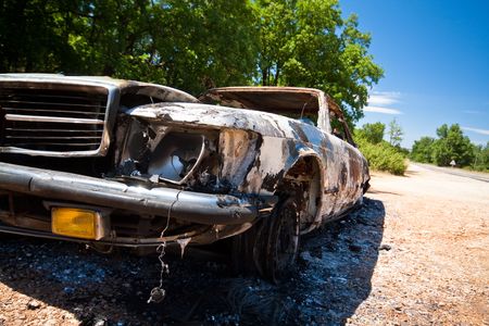 Burnt and destroyed car by the roadsideの写真素材