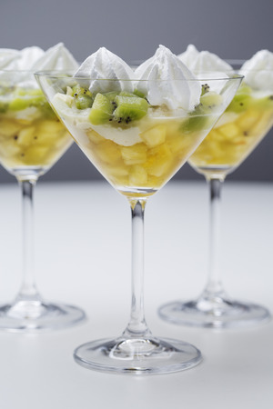 kiwi and pineapple dessert with white cream in martini glassesの写真素材