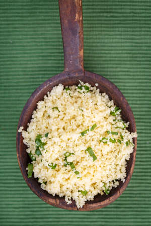 couscous with chives in old wooden spoonの写真素材