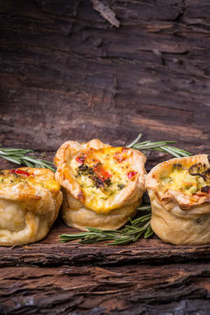 three broccolli tarts with cheese and rosemary on barkの写真素材