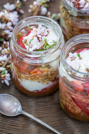 layered dessert - strawberries, grains, sauce and whipped cream in jarの写真素材