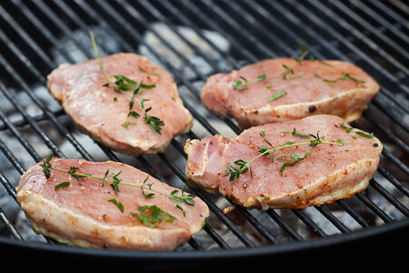 raw meat pieces on grill with thymeの写真素材
