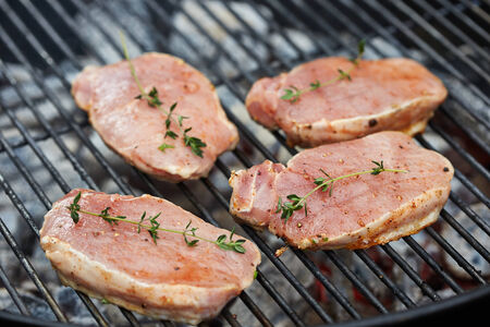raw meat pieces on grill with thymeの写真素材