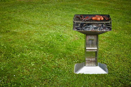 prepared sausages on grill on grass backgroundの写真素材