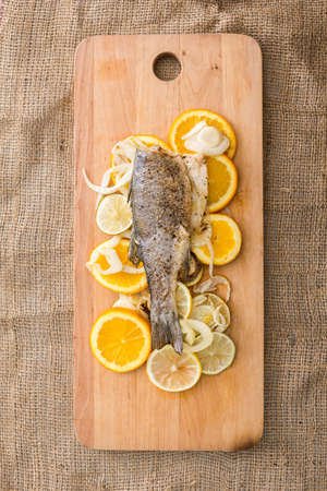 prepared fish with lemon on wooden cutting board. Top view