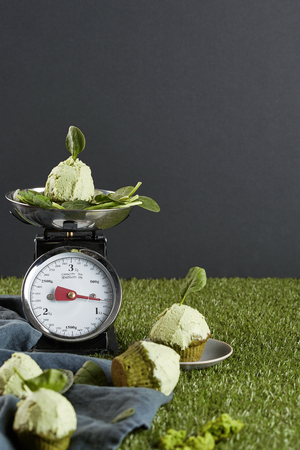 a cupcake with pistachio topping on the scales in the grey backgroundの写真素材