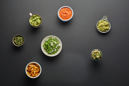 horisontal top view of vegetarian tomato sauce, guacamole, pesto, salad and pineapple pieces...
