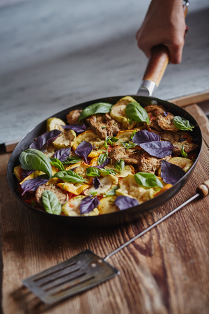 an image of vegetarian saute decorated with basil leaves and served in the frying-panの写真素材