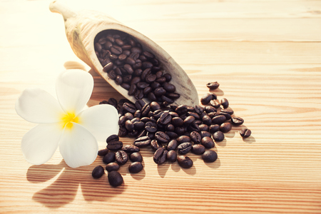 Coffee beans and Plumeria flower on wood background.の写真素材