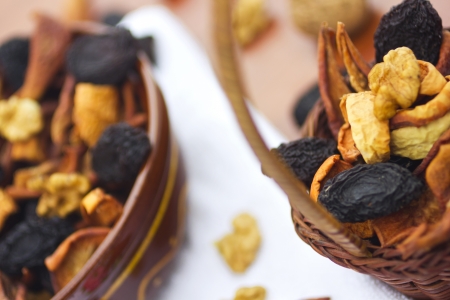 Dried fruits and nuts in bowl and basket on tableの写真素材