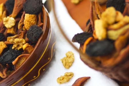 Dried fruits and nuts in bowl and basket on tableの写真素材