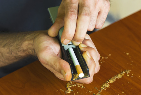Man rolling cigarettes using fresh tobaccoの写真素材