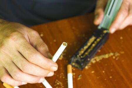 Man rolling cigarettes using fresh tobaccoの写真素材