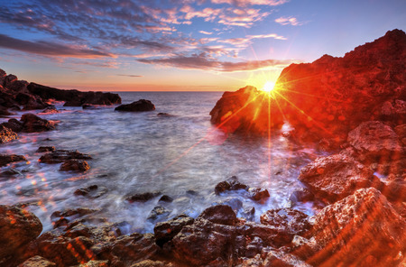Beautiful sunrise on rocky shore and dramatic sky cloudsの写真素材