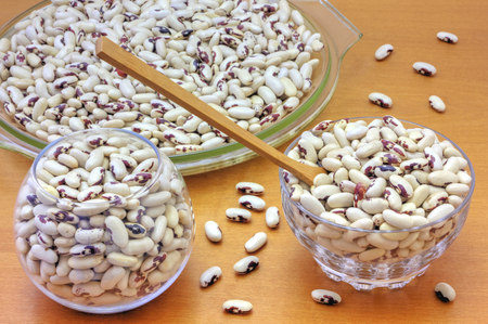 Colorful haricot beans in glass bowls on wooden background