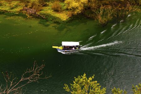 Beautiful landscape view with boat on the river and colorful autumn forest