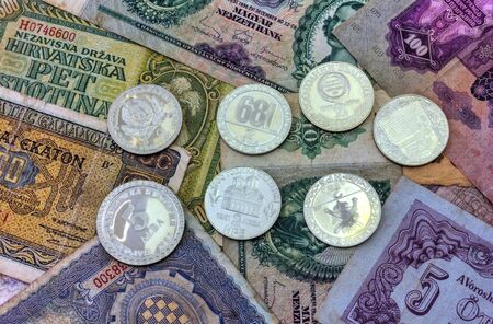 A pile of anniversary coins of republic of Bulgaria over a background of banknotes close up viewの写真素材