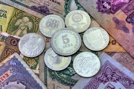 A pile of anniversary coins of republic of Bulgaria over a background of banknotes close up viewの写真素材