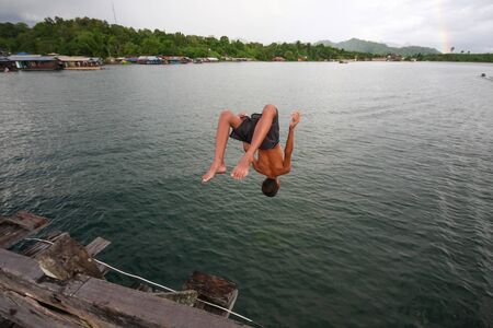 A boy flipping into the scary dark and deep river